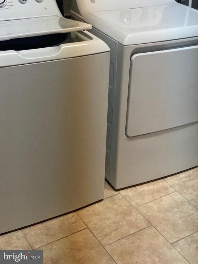 clothes washing area featuring laundry area, light tile patterned floors, and washer and dryer