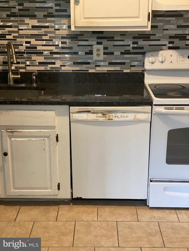 kitchen with dark countertops, white appliances, white cabinets, and a sink