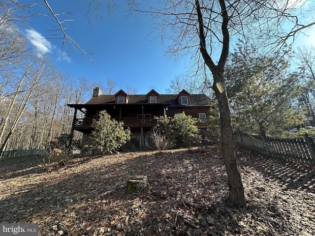 back of house with a chimney and fence