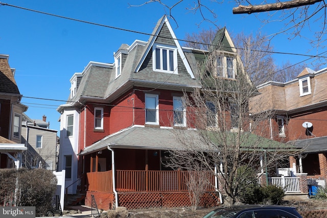 view of front facade featuring a shingled roof, a porch, and brick siding