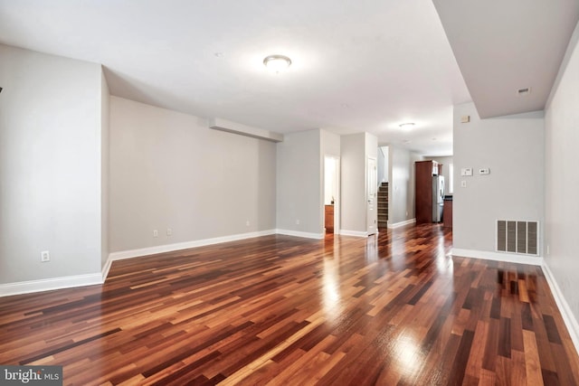 unfurnished room featuring stairway, baseboards, visible vents, and dark wood-type flooring