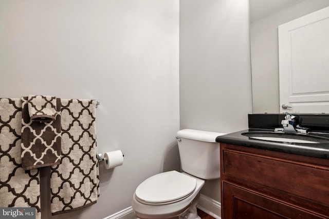 bathroom with baseboards, vanity, and toilet