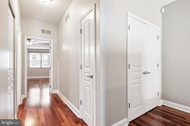 hallway featuring baseboards, visible vents, and dark wood-type flooring