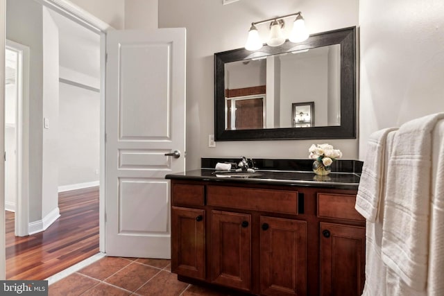 bathroom featuring baseboards, tile patterned flooring, vanity, and a shower with door