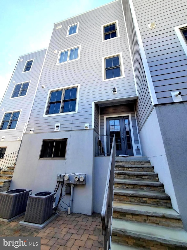 rear view of house featuring a patio, cooling unit, and stucco siding