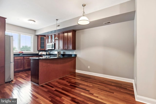 kitchen with dark wood finished floors, dark countertops, visible vents, appliances with stainless steel finishes, and a peninsula