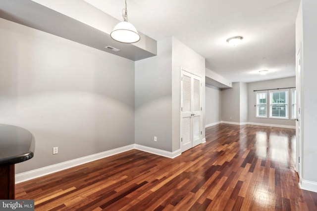 interior space with baseboards, visible vents, and hardwood / wood-style floors