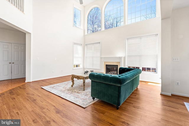 living area with plenty of natural light, baseboards, wood finished floors, and a glass covered fireplace