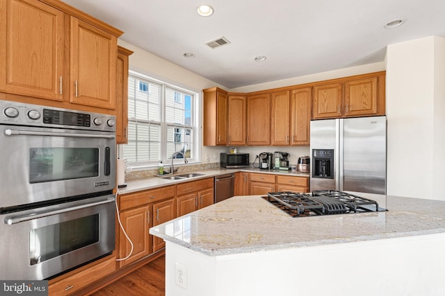 kitchen with visible vents, light stone counters, dark wood-type flooring, stainless steel appliances, and a sink