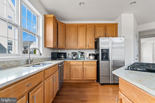 kitchen featuring light stone counters, recessed lighting, dark wood-style flooring, a sink, and black appliances