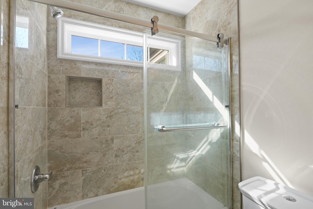 bathroom with toilet and combined bath / shower with glass door