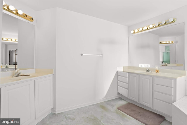 bathroom featuring two vanities, a sink, and baseboards