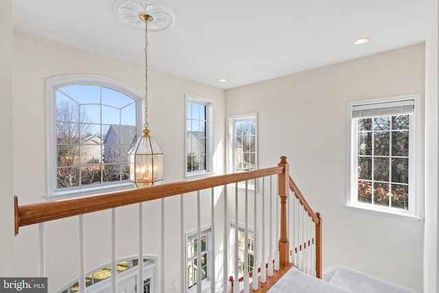 hall featuring recessed lighting, plenty of natural light, and an upstairs landing