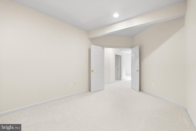 unfurnished bedroom with baseboards, beamed ceiling, and light colored carpet