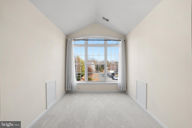 carpeted spare room with lofted ceiling, visible vents, and baseboards