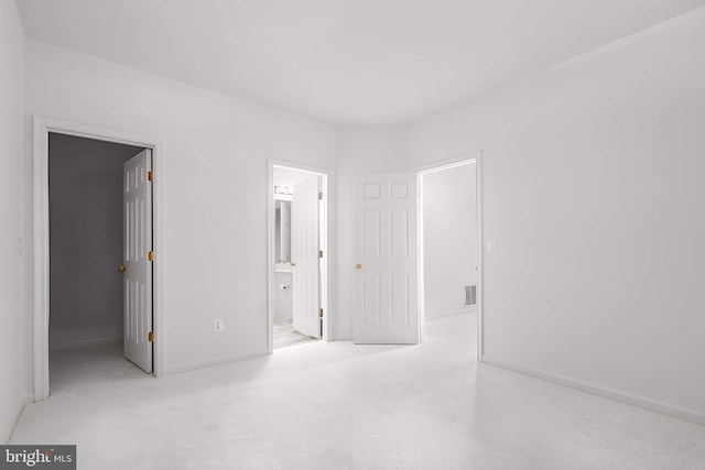 unfurnished bedroom featuring a walk in closet, visible vents, baseboards, and ensuite bathroom