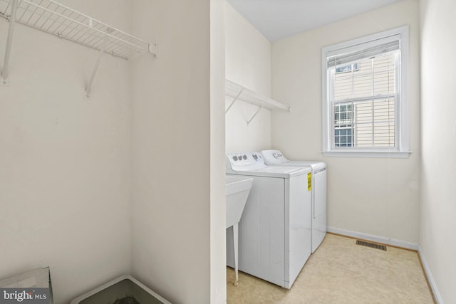 clothes washing area with laundry area, washing machine and clothes dryer, visible vents, and baseboards