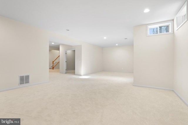 basement featuring light carpet, baseboards, visible vents, stairs, and recessed lighting