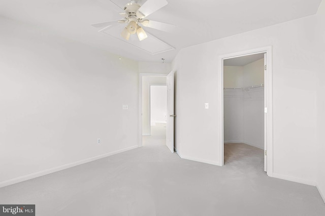 unfurnished bedroom with a ceiling fan, a walk in closet, a closet, and baseboards