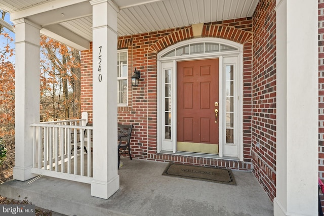 property entrance with a porch and brick siding