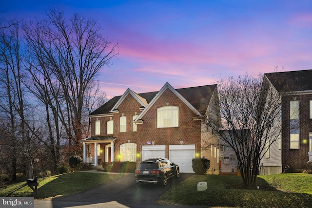 view of front of property with aphalt driveway, a front yard, brick siding, and an attached garage