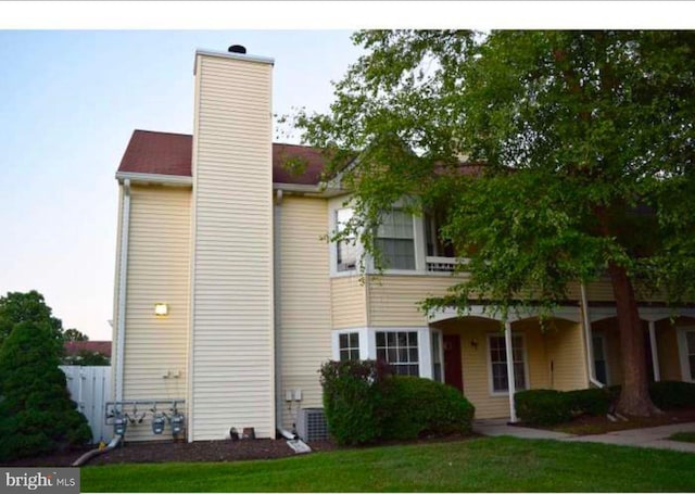 view of front of house featuring a chimney, fence, and a front yard