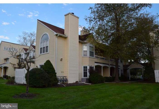 view of side of property with a yard and a chimney