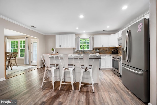 15185 Day Rd, Goldsboro, MD 21636 - kitchen featuring appliances with stainless steel finishes, light wood-style flooring, white cabinets, a kitchen breakfast bar, and ornamental molding