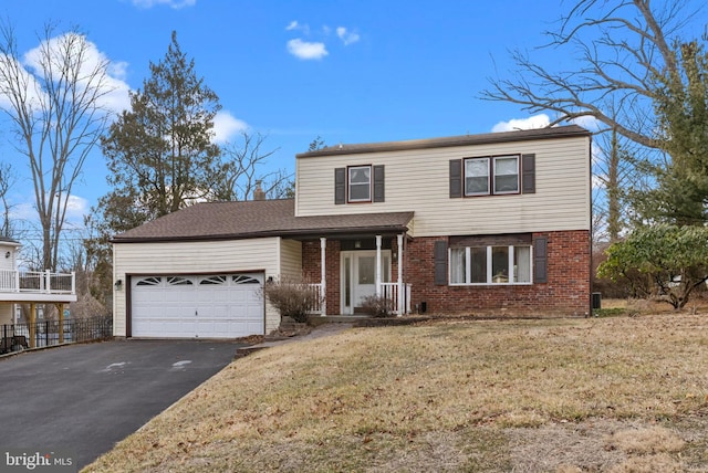 traditional-style home featuring an attached garage, a front lawn, aphalt driveway, and brick siding