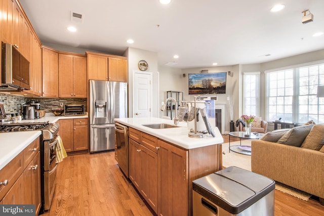 kitchen featuring open floor plan, appliances with stainless steel finishes, light wood-style floors, and a sink