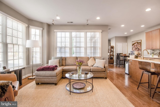 living room featuring light wood finished floors, visible vents, recessed lighting, and baseboards