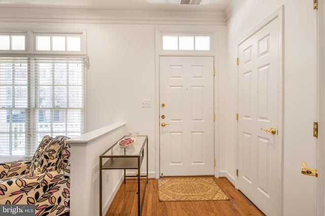 entryway featuring light wood-style flooring, baseboards, visible vents, and ornamental molding