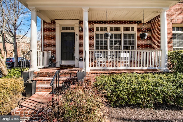 property entrance with brick siding and covered porch