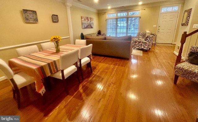 living area featuring decorative columns, wood-type flooring, stairs, and crown molding