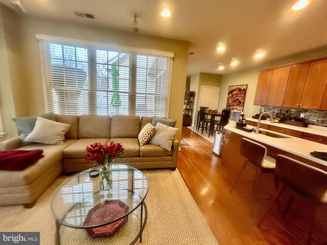 living area with light wood-type flooring, visible vents, and recessed lighting