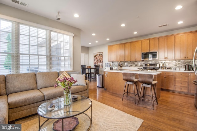 kitchen featuring stainless steel microwave, range, tasteful backsplash, and visible vents