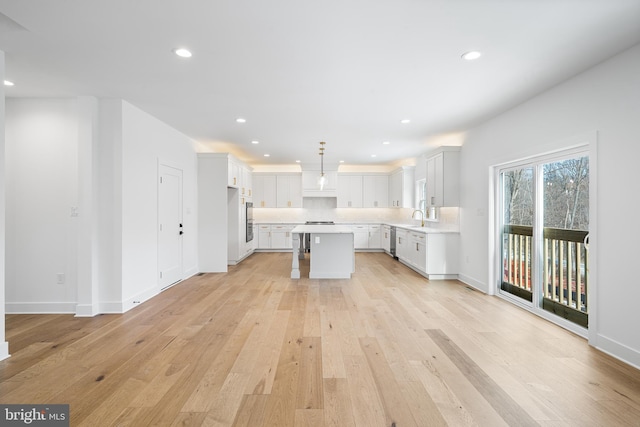 kitchen featuring a center island, light wood finished floors, recessed lighting, light countertops, and a sink