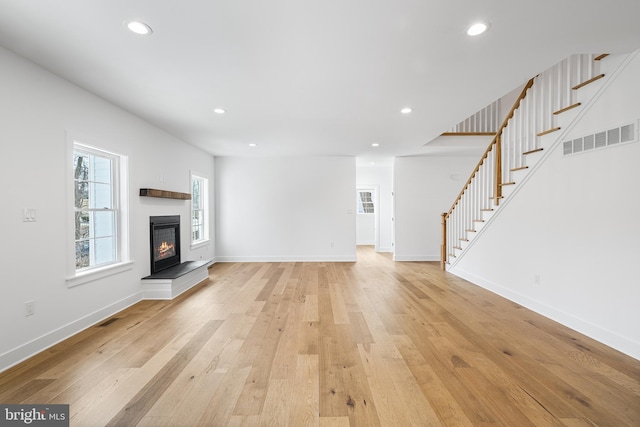 unfurnished living room with stairway, light wood-style flooring, visible vents, and recessed lighting