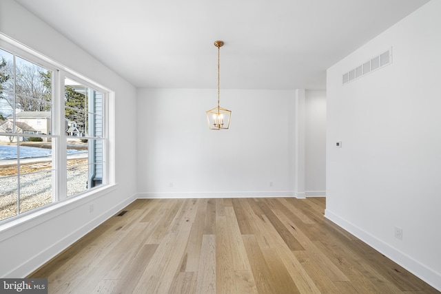 unfurnished dining area featuring a notable chandelier, light wood-style flooring, visible vents, and baseboards