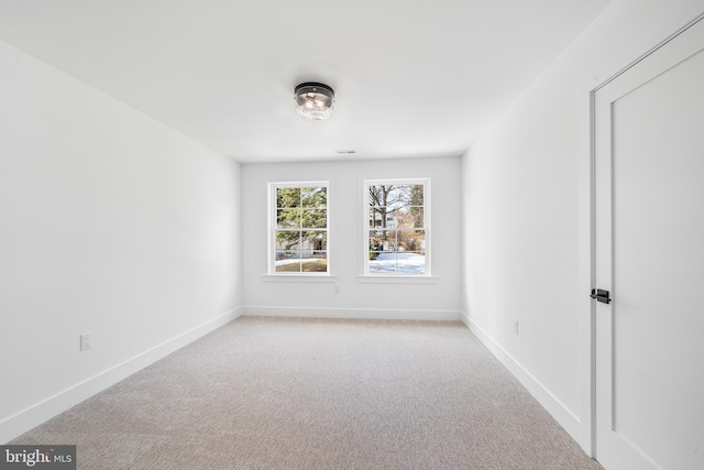 empty room featuring light carpet, visible vents, and baseboards