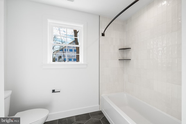 bathroom with baseboards, washtub / shower combination, toilet, and tile patterned floors