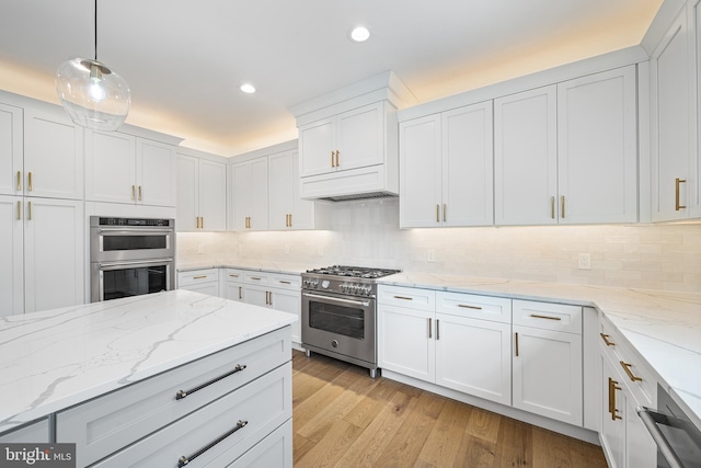 kitchen featuring white cabinetry, light wood-style floors, appliances with stainless steel finishes, decorative backsplash, and decorative light fixtures