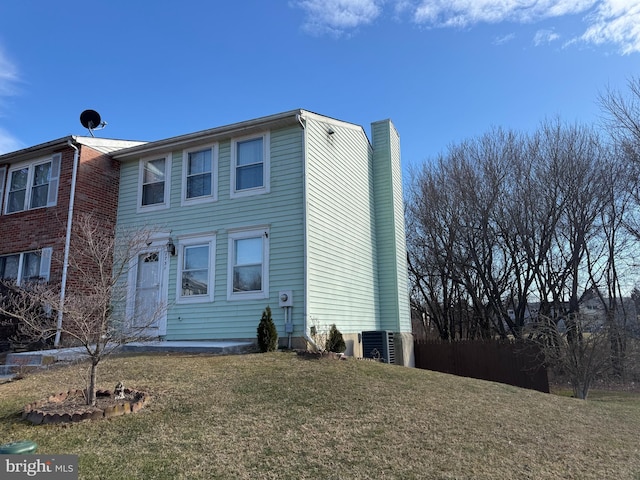 view of front facade with a front lawn, a chimney, and central air condition unit