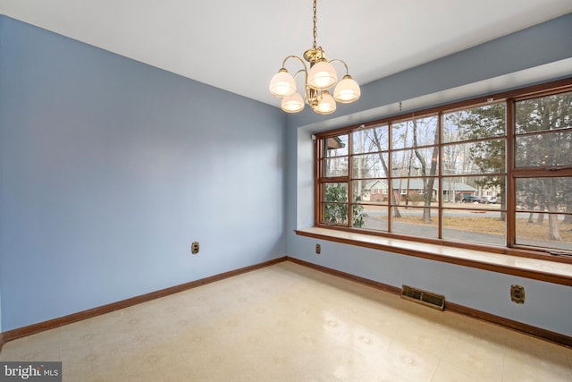 spare room with baseboards, visible vents, and a chandelier