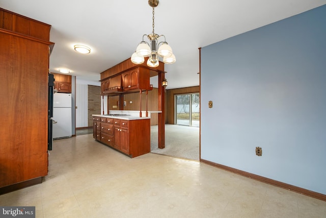 kitchen with pendant lighting, a notable chandelier, light countertops, freestanding refrigerator, and baseboards