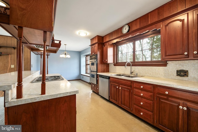 kitchen with decorative light fixtures, light countertops, decorative backsplash, appliances with stainless steel finishes, and a sink