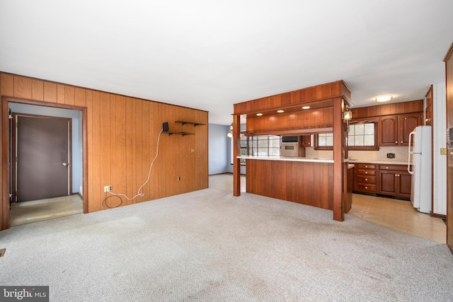 unfurnished living room featuring light colored carpet and wood walls