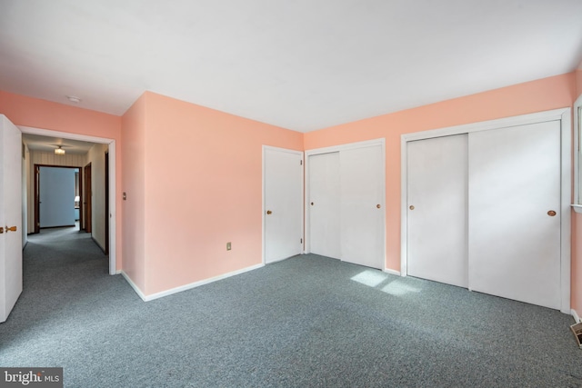 unfurnished bedroom with carpet, two closets, and baseboards