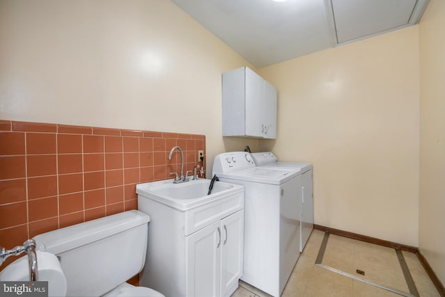 laundry area with light tile patterned flooring, washing machine and dryer, laundry area, tile walls, and baseboards