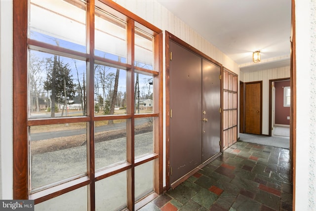 hallway with stone tile flooring and wallpapered walls